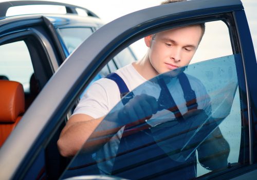 Welcome to our car service station. Closeup image of a handsome car mechanic attaching tinting foil to car window and smiling at camera in specialized service station SSUCv3H4sIAAAAAAAEAJ2TPW+DMBCG90j5DxFzQAbMRzt26xCpUscqgzGXxIrBETZpooj/XttAahBduvneu/e5O3Q81qvNxiuIZNR73TxMpGPGeStVQxQTtZbRdtChZEo0jHAjGq2zGU8qoloJ0iAGiRIFR13bi4N/7PPVx5sxYZPaoVOet3U02RZWG6Vu+29n/9iPq5Aj1PT+O5uxnFqloJFK0LM7pE6F8QQeRU/u/ql7zDovJ6HEzI5u6S1KkiBMJphJYGtiZGoW2AcN5YzMuDFCCUJZEOZTcIRMAidBGmdLtLIBUknFKpjvGWYTUIjzSYzxEq5gxz9Xf2slq0HK4BOaK6P6HFzee12aQ7sHOyYpcE5qEO205APEhUOwg3pxE7gIyZTtLGet3WH7R+fcbAMcSH+zg8lLyoJEIcb+AdLUx3lK/BxD6pOXLKNhGAHKqEX2A3jnb30ulXv1V1aCcGLSlkw4P8BVUMKNIXYmofoTiMq61qvuB05HEcOSAwAA