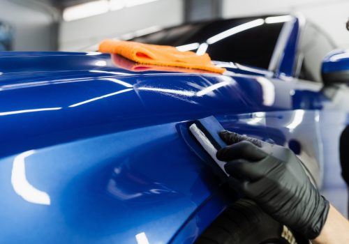 Process of applying ceramic protective coat on body car using sponge in detailing auto service. Car service worker apply ceramic coating to protect the car body from scratches